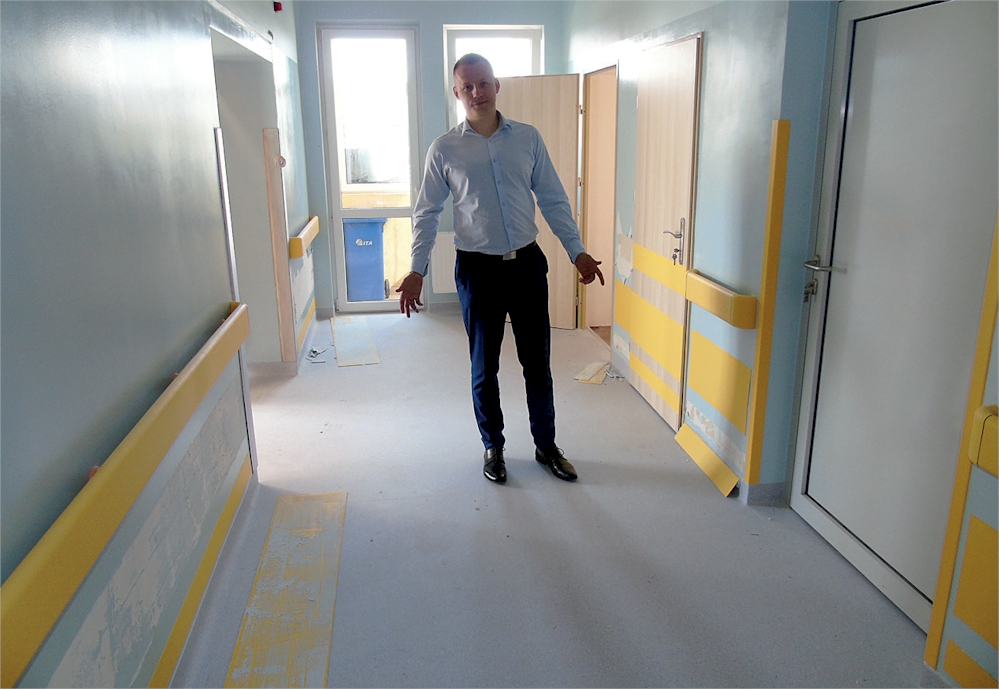 Prezes szpitala Krzysztof Zarychta na korytarzu urologii załamuje ręce, patrząc na stan ścian i wejść do pokojów pacjentów